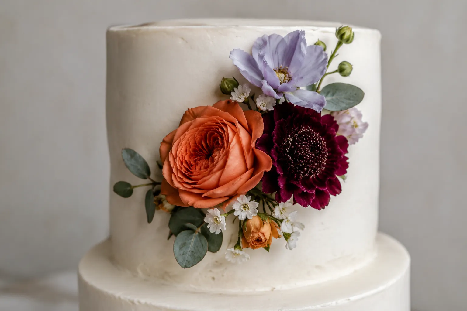 Cake with concentrated accent-colored flowers and focal decoration